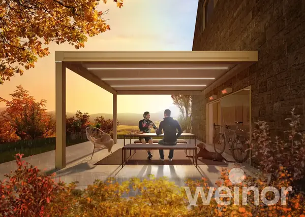 Terrassenüberdachung mit LED-Beleuchtung am Haus, zwei Personen sitzen draußen
