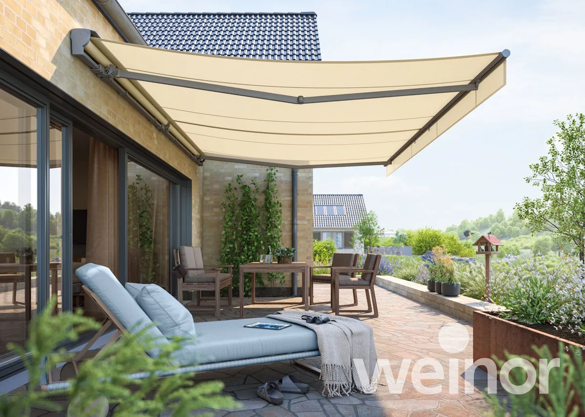 Beige Terrassenmarkise als Sonnenschutz über Sitzgruppe am Haus auf Terrasse
